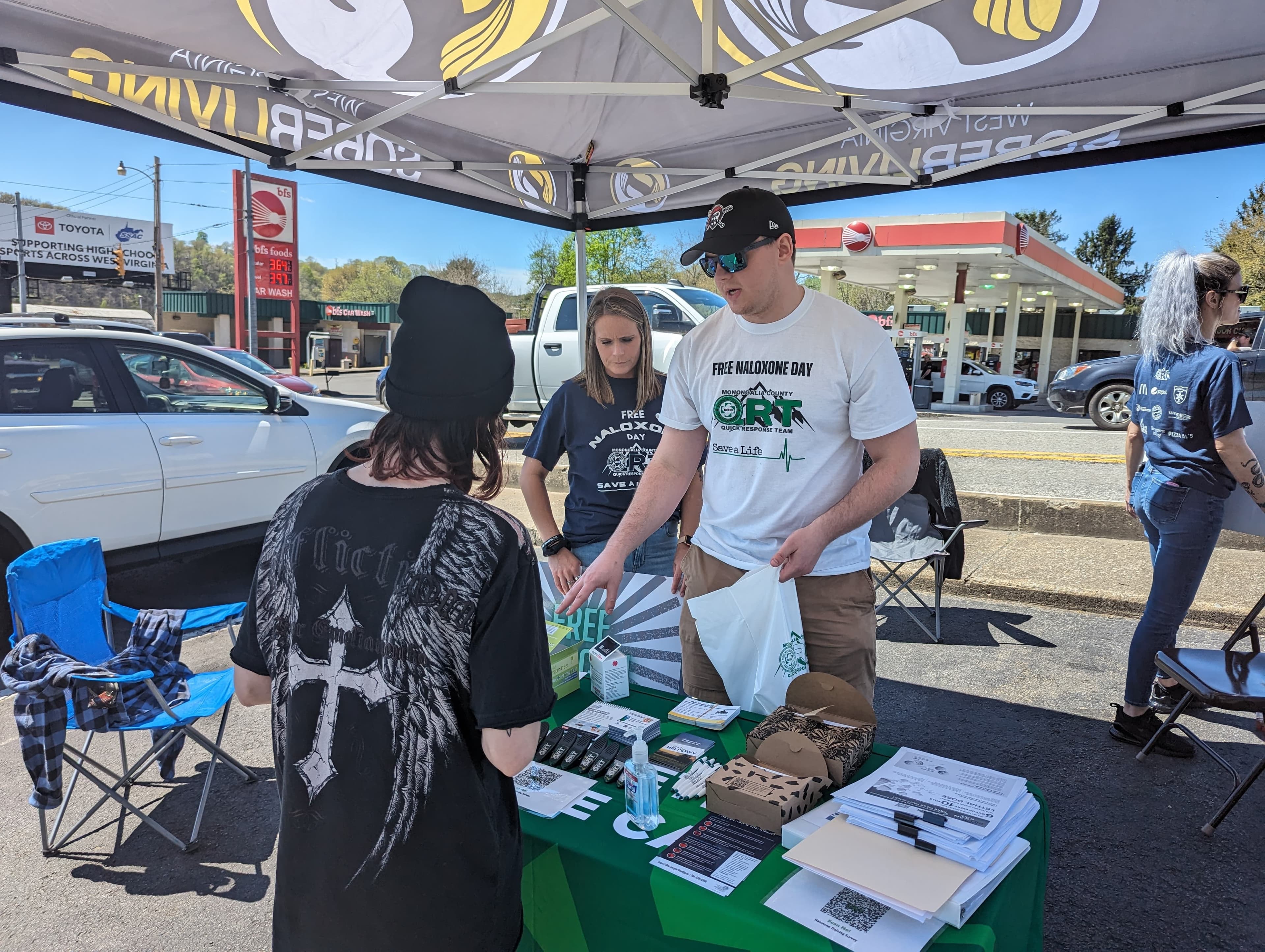 Teisha Prim and Jacob Workman talk about naloxone with an individual during the Monongalia County QRT's Free Naloxone Day in April 2024.